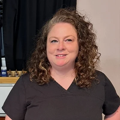 Jess smiling in black scrubs.