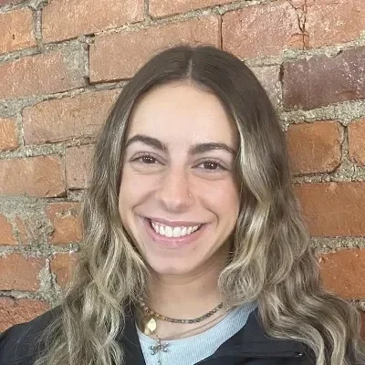 Nicki Impal smiling in front of a brick wall.